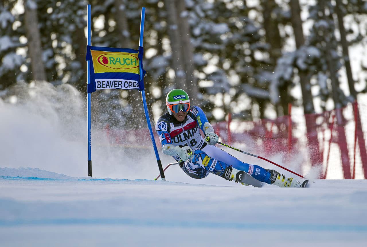 A competitive skier in Beaver Creek, Colorado, defies gravity as they speed around a blue marker and appear to be almost sitting sideways just inches from the ground.