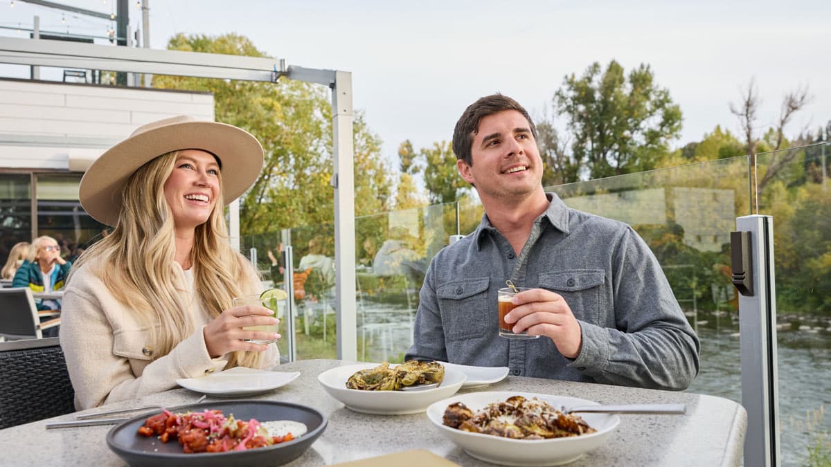 Couple dining and drinking at a restaurant along the Yampa River in Steamboat Springs, Colorado.