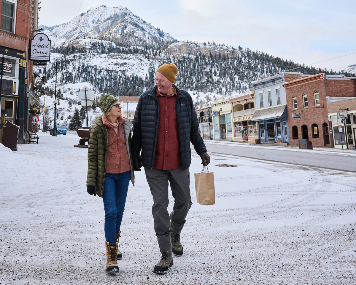A couple strolls through snow-blanketed Ouray, Colorado in winter