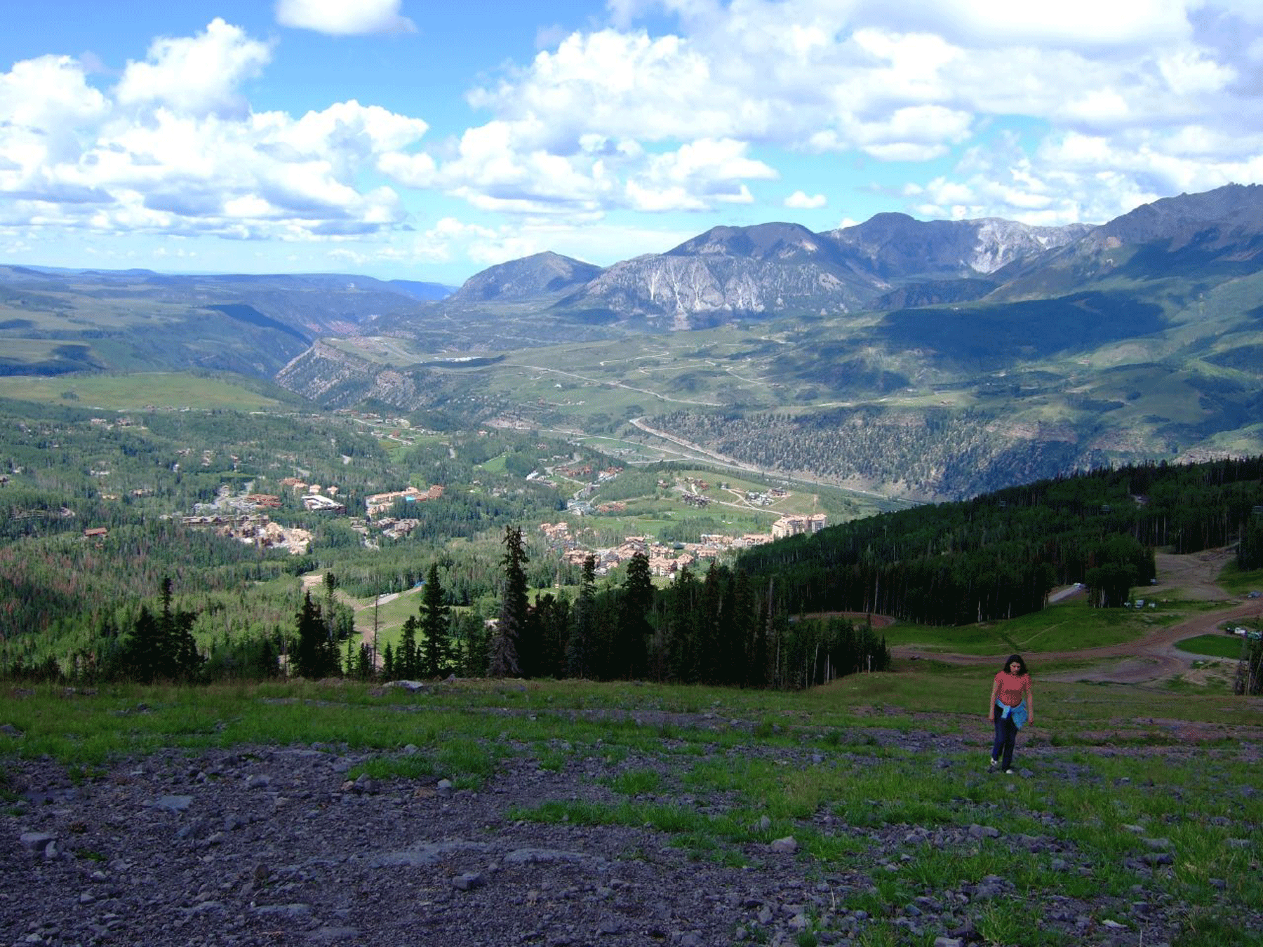 A vast expanse of green meadows and purple peaks