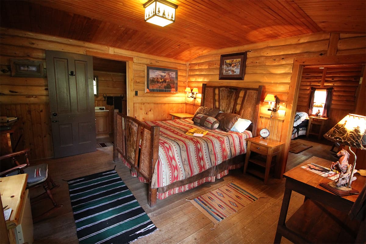 A log cabin at Bar Lazy J Guest Ranch is decorated with homey, Western touches like horse lamps, a sliding barn door and a wooden rocker.