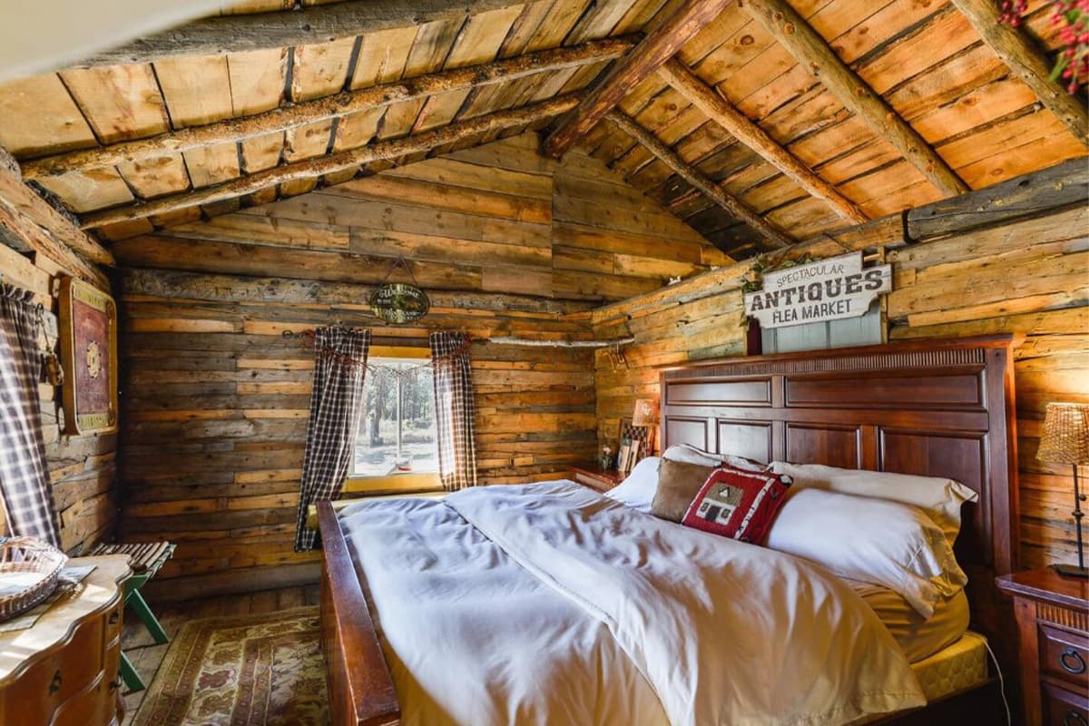 A bed is made with plush, white linens and sits awaiting guests in a rustic cabin near Lake George, Colorado.