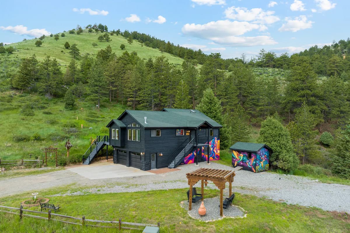 Amid verdant green peaks peppered with pines lies Hummingbird Hill, a black-painted building near Idaho Springs, Colorado.