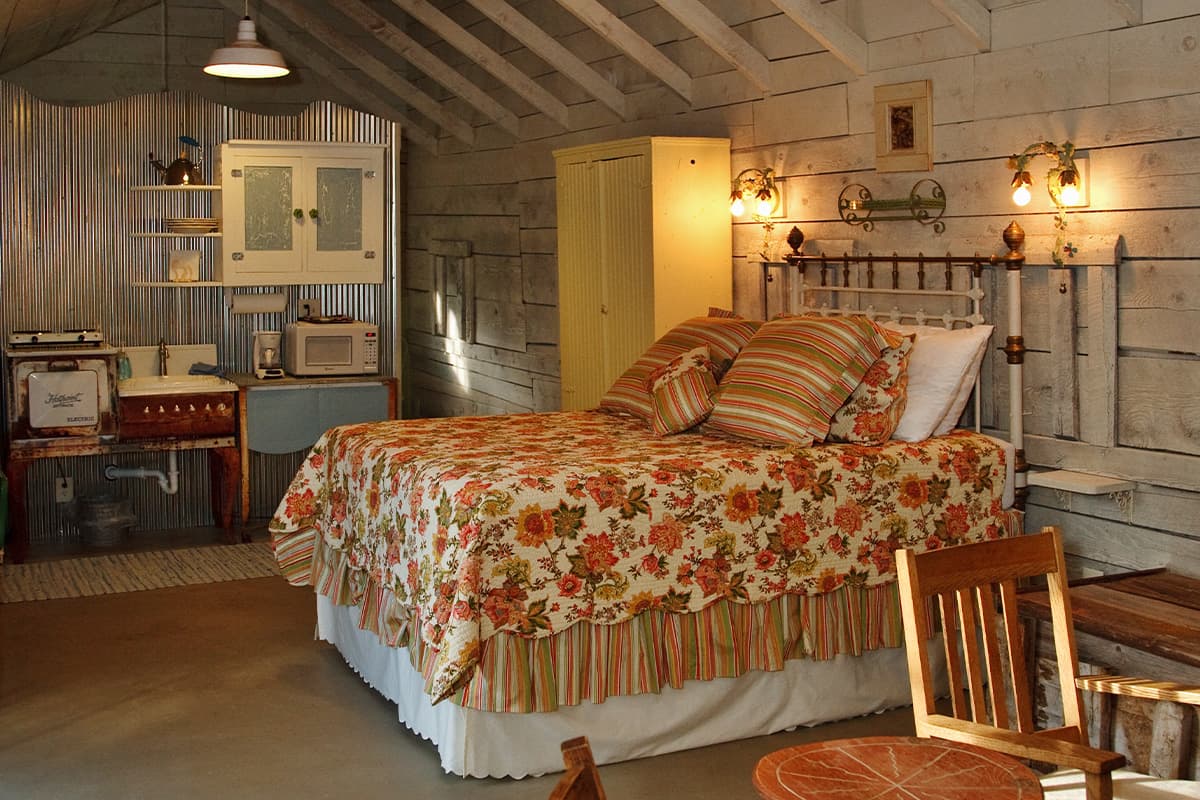 A bed with floral and striped patterned sheets awaits guests in a high-ceiling barn room at Four Mile Creek B&B in Glenwood Springs, Colorado.
