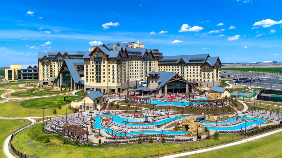 Gaylord Rockies Resort & Convention Center seem from the exterior with its lazy-river water park in the foreground, verdant green grass and a bluebird-blue sky in the background.