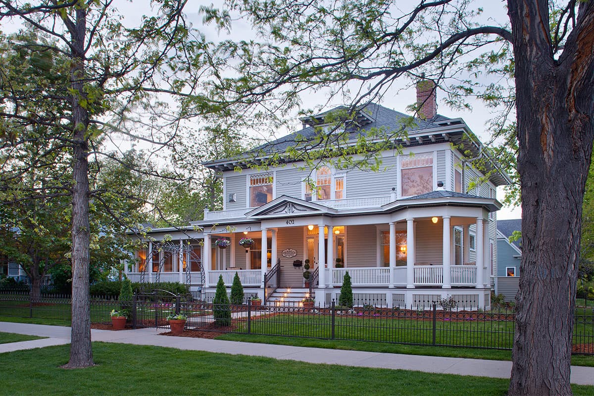 Edwards House, a grand multi-story bed-and-breakfast, is set on a peaceful block with tall, verdant trees near Fort Collins, Colorado.