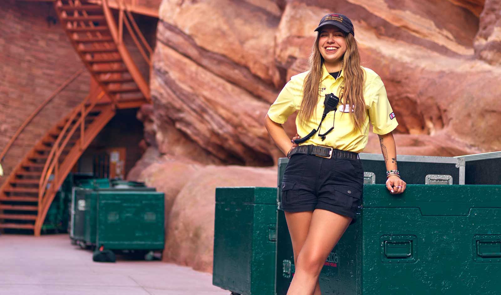 A woman stands at Red Rocks in an employee uniform