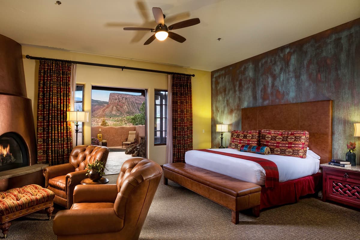 A guest room at the Gateway Canyon Resort in Gateway, Colorado, is decorated with leather accent pieces and an adobe-style fireplace and features a patio overlooking the canyon valley.