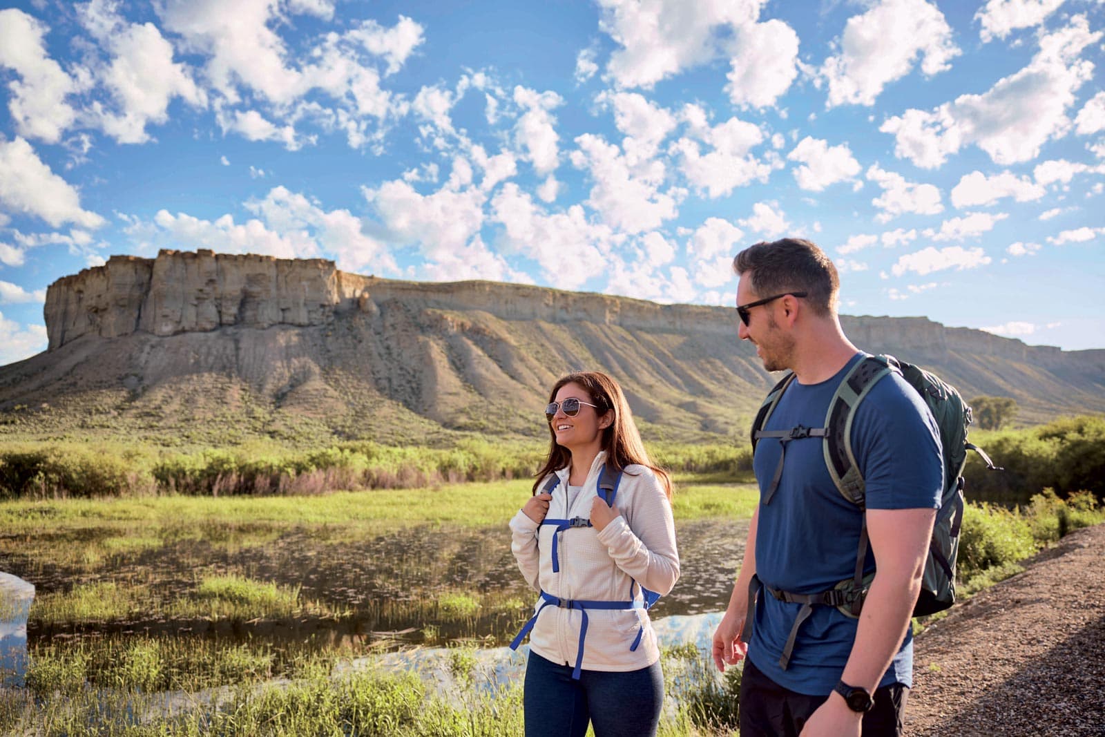 Two hikers walk a trail next to a bluff near Kremmling