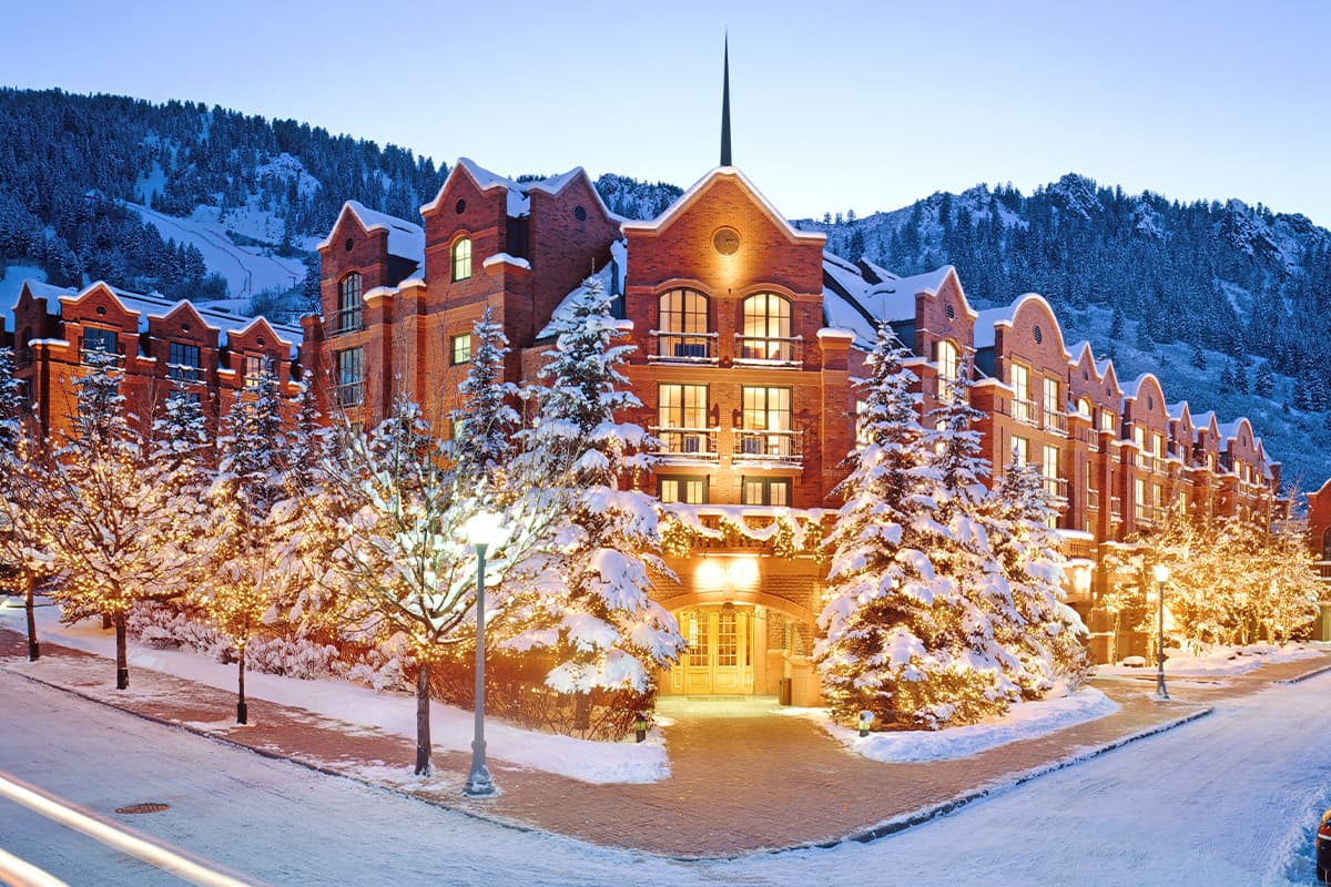 The St. Regis Aspen Resort in Aspen, Colorado, is covered in a blanket of soft, fluffy snow with pine-peppered slopes in the background.