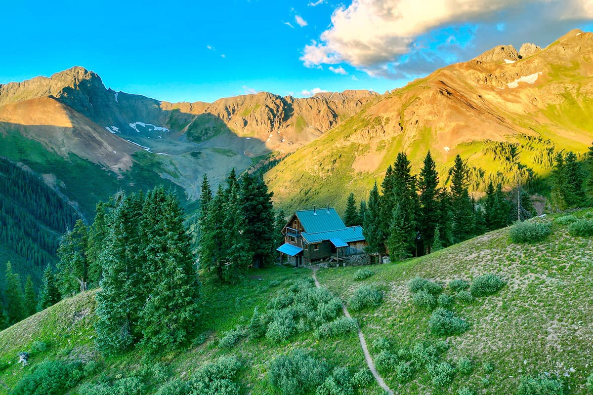 Near Silverton, Colorado, the OPUS Hut stands on a mountainside slope sheltered by copses of towering pines.