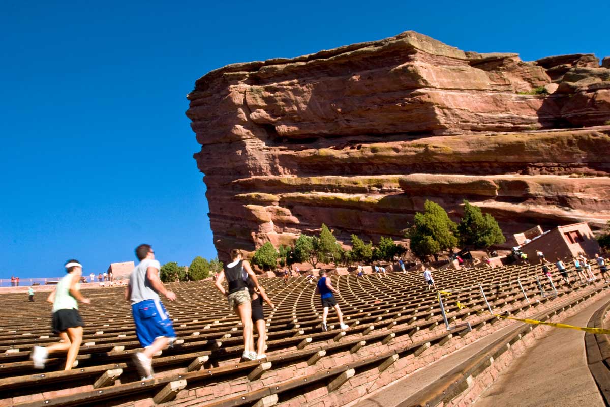 Runners race through the stairs at Red Rocks Park & Amphitheatre in Morrison, Colorado. The area is dominated by a giant, red rock formation at one end of the amphitheater.
