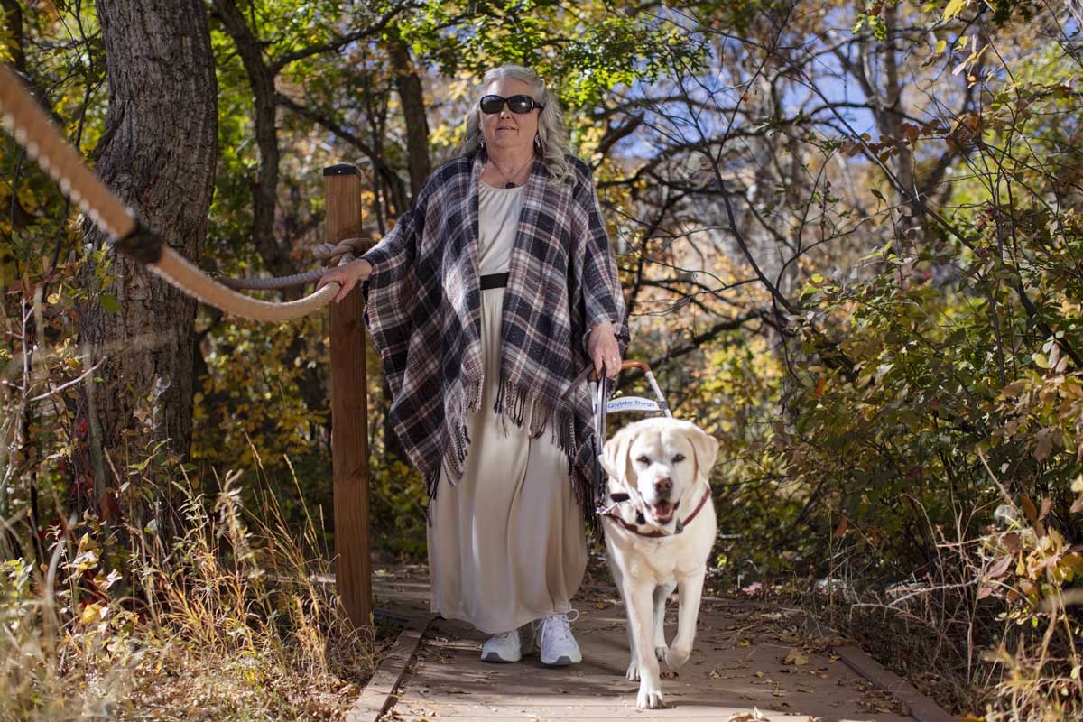 A visually-impaired person walks on a trail with a seeing-eye dog