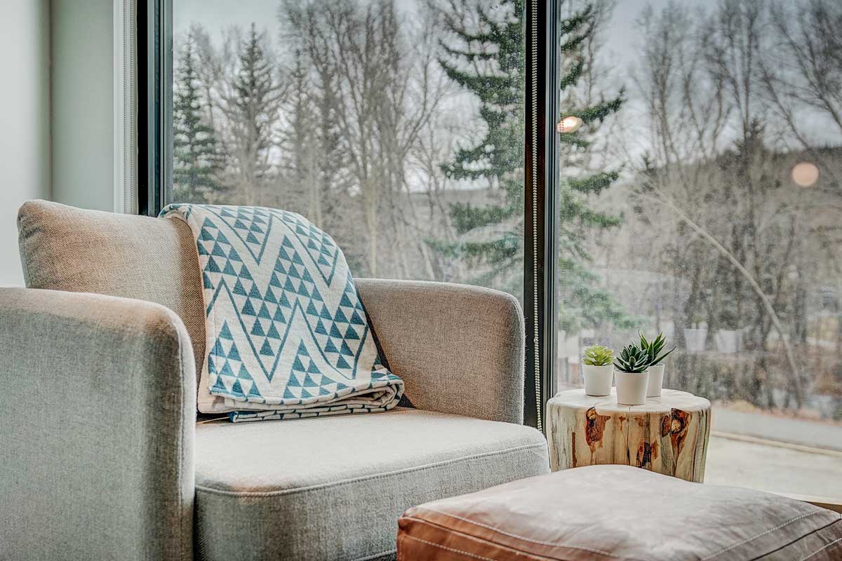 A cozy chair to read in with a window view behind it at The Pad in Silverthorne