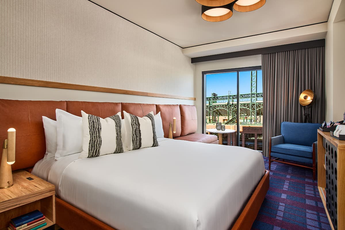 A bedroom at The Rally Hotel in Denver features bright-white linens and a padded leather headboard.