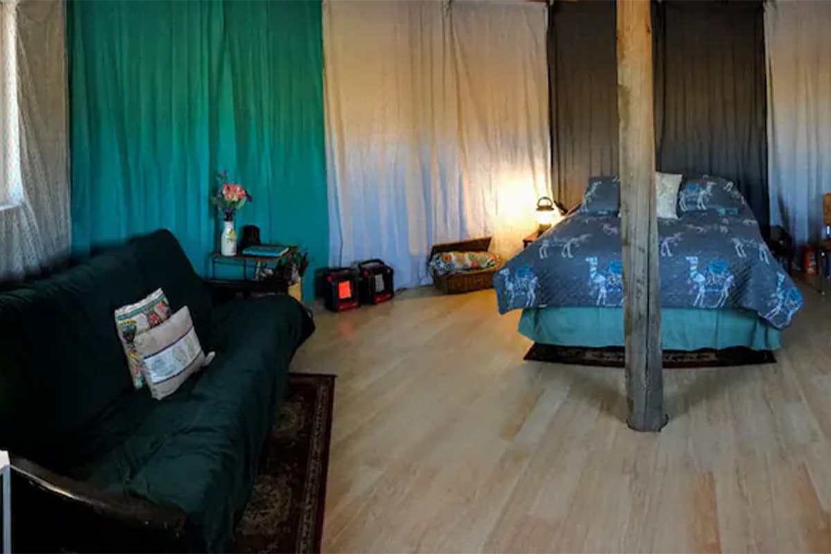 The inside of a yurt near Capulin, Colorado, is draped with white and teal swathes of fabric, a cushy couch and a large bed.