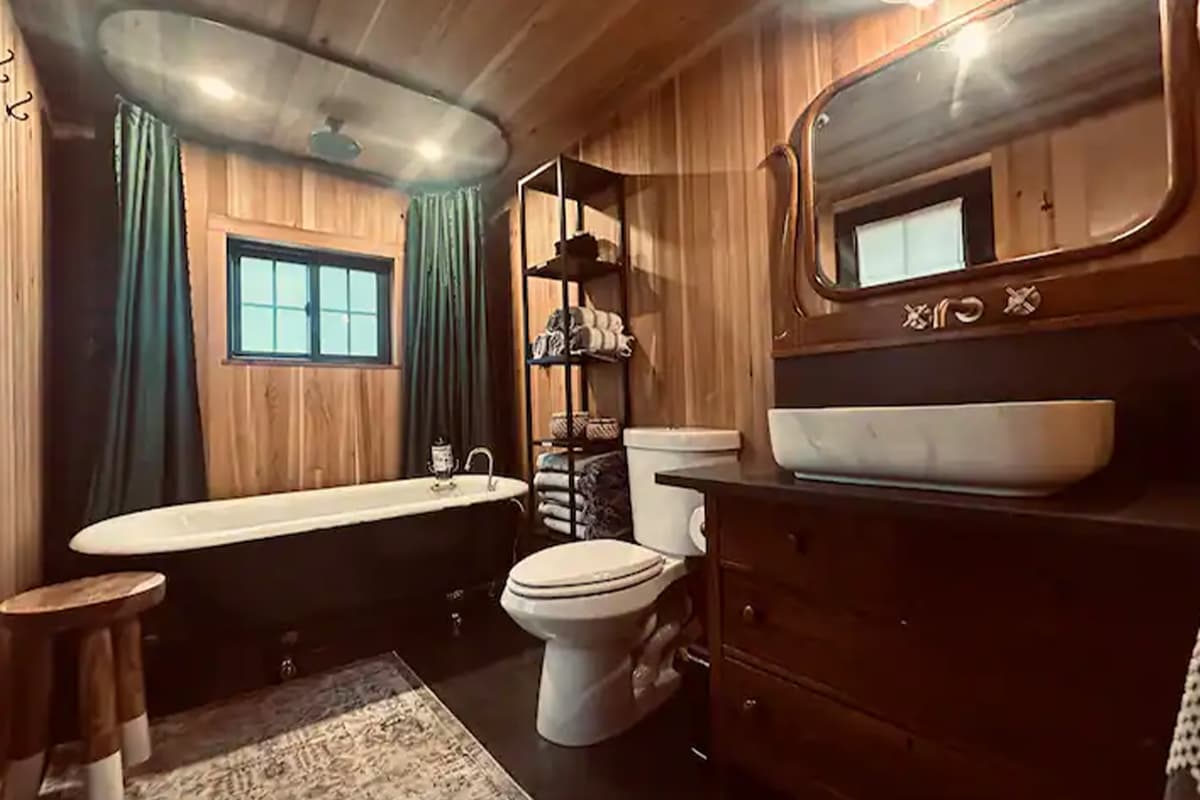 In a cabin near Conifer, Colorado, a wood-paneled bathroom houses a clawfoot tub and rain-style shower.