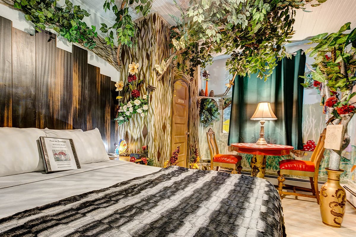 The green-leafed branches of a fake tree spread across the ceiling of the woodland-themed Enchanted Forest room at The Oasis on Eisenhower