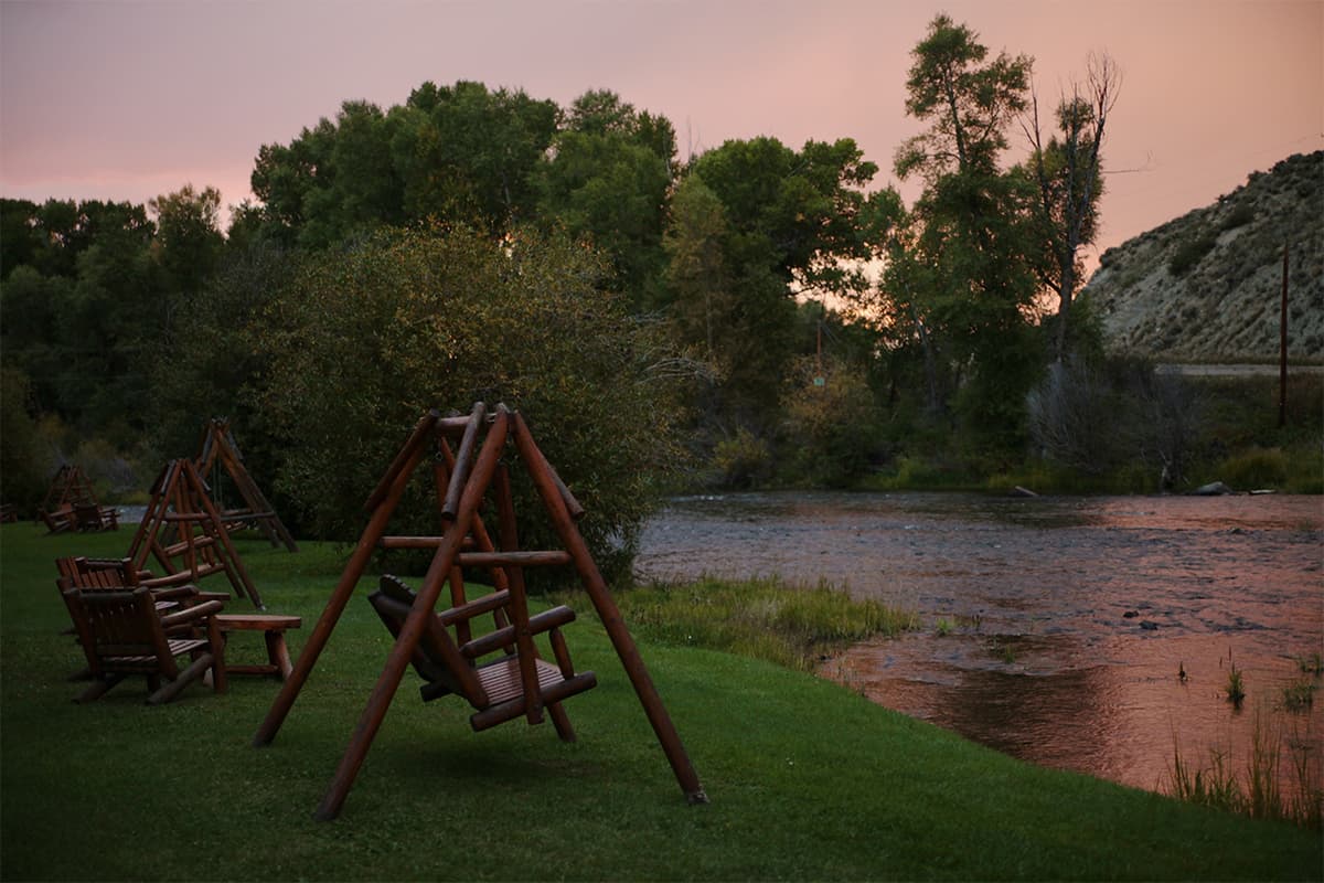 A soft sunset of muddled pink and purple signals night time over the trees and bankside swings at Bar Lazy J Guest Ranch.