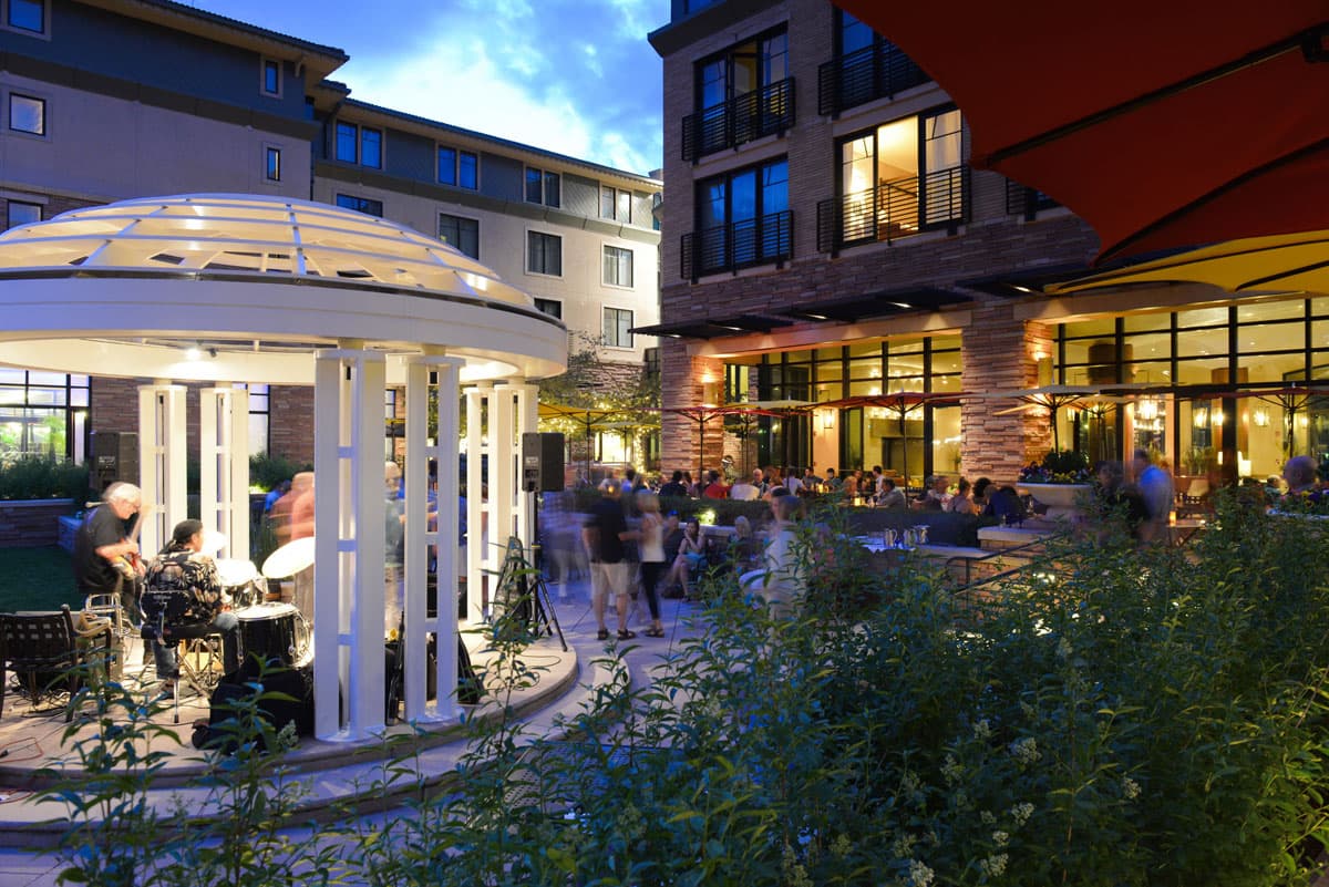 People gather around Boulder's St. Julien Hotel & Spa in the evening as musicians play in a gazebo.