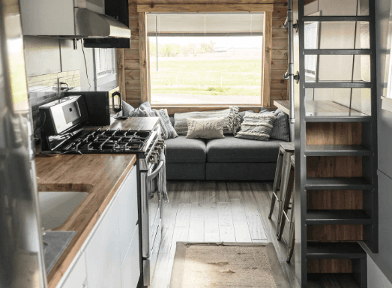 Interior of tiny house on Hudson, Colorado, horse farm with a picture window and a comfy gray couch