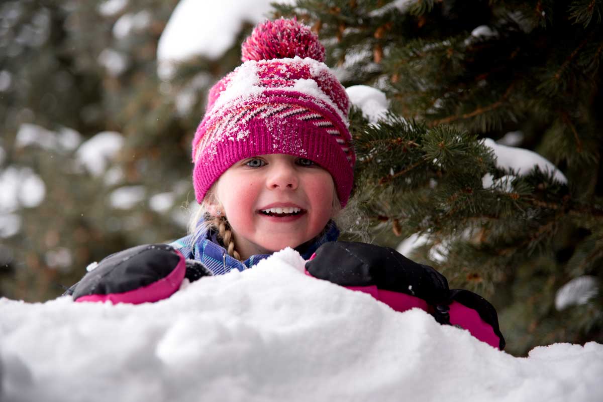 Young child wearing a pink hat plays in the snow at Latigo Ranch