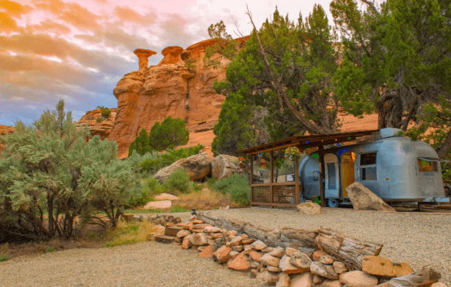 The Canyon Hideout Bungalow airstream seen with red-rock formations behind it