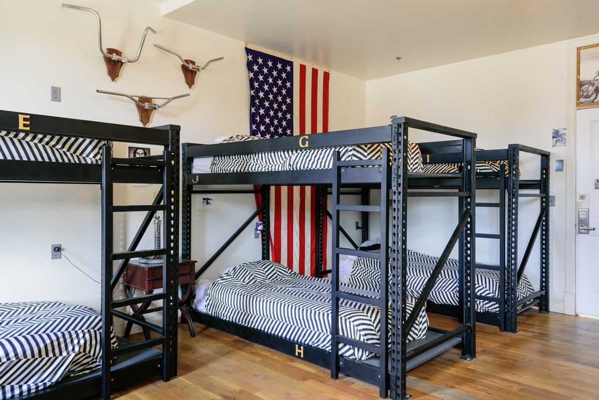 Slate-colored metal bunk beds line a guest room at Hostel Fish in Denver with an American flag int he background