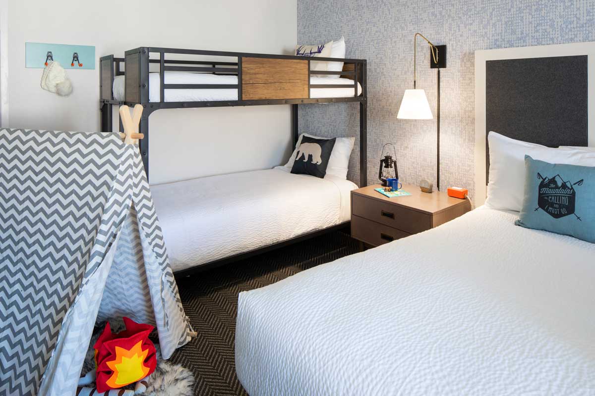 A guest room for families at Gravity Haus Steamboat. The room has a comfy bunkbed and a king bed.