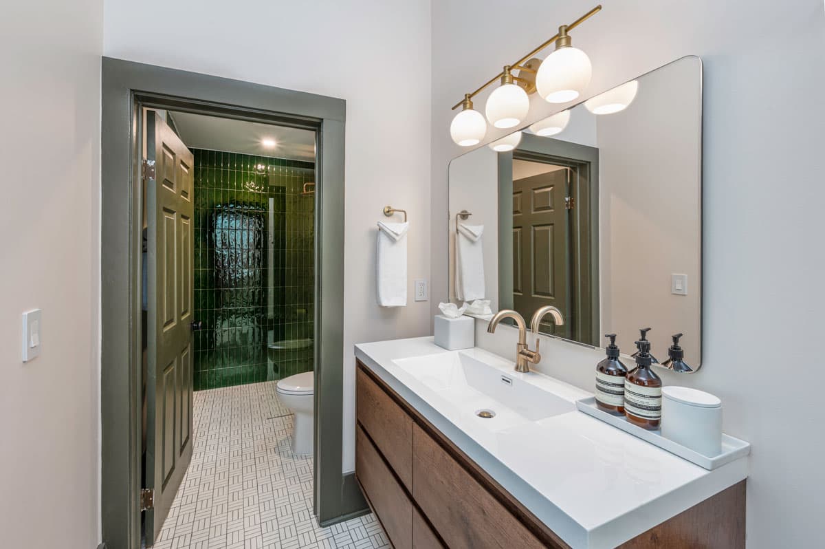 An updated bathroom with a wooden vanity and tiled shower at The Rochester Hotel in Durango