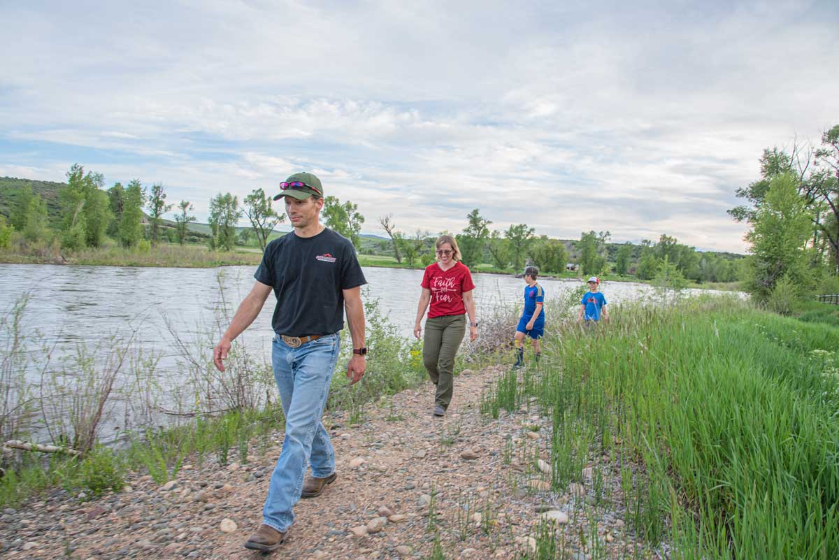 A family walks along a gravel trail by the river at Yampa River State Park.