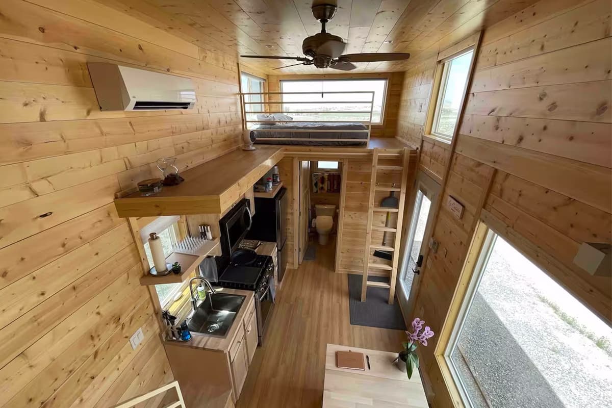An aerial view of a tiny home in Montrose, Colorado, shows many windows, a loft with ceiling fan and a complete kitchen.