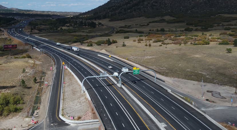 Aerial view of South Gap Express Lanes winding through an open field of scattered trees and a distant mountain in Colorado.