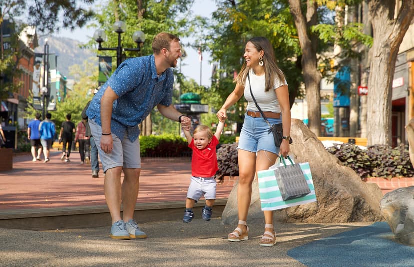 A family walks down Pearl Street in Boulder Colorado with the parents swinging the baby between them