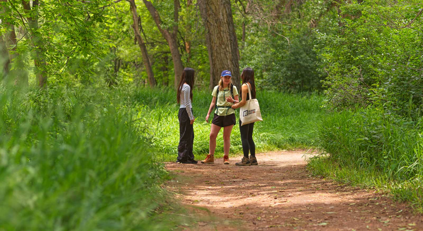 Three woman stand on a dirt trail