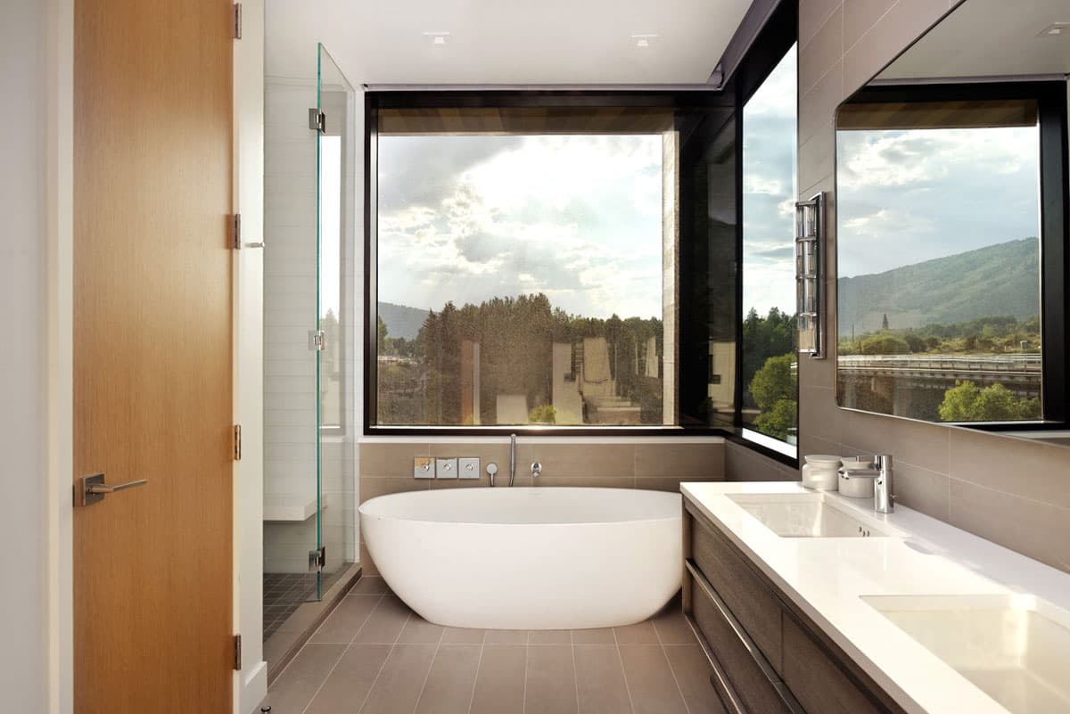 Well-lit bathroom filled with natural light and a bathtub centered in a bathroom in Aspen, Colorado.