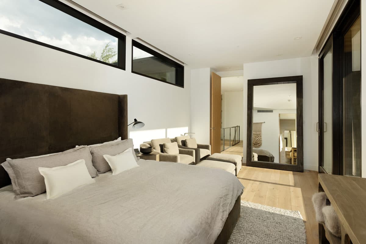 A bed with neutral colored bedding with sunshine flowing through the bedroom window, revealing a bright room in Aspen, Colorado.