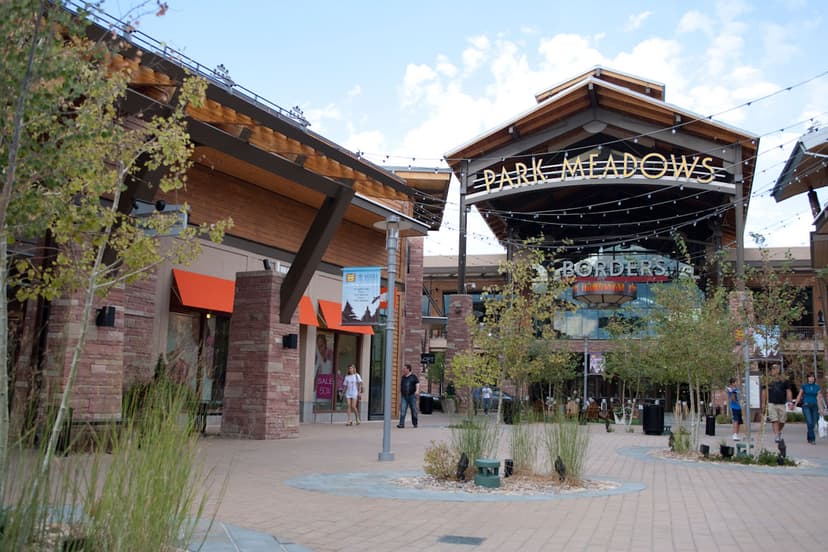 The entrance of Park Meadows Mall in the summer with green trees and plants and a "Borders" book store in the distance.