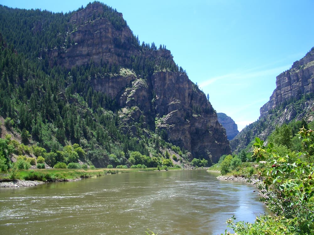 A flowing Colorado River winds through the valley between the verdant walls of Glenwood Canyon near Glenwood Springs.
