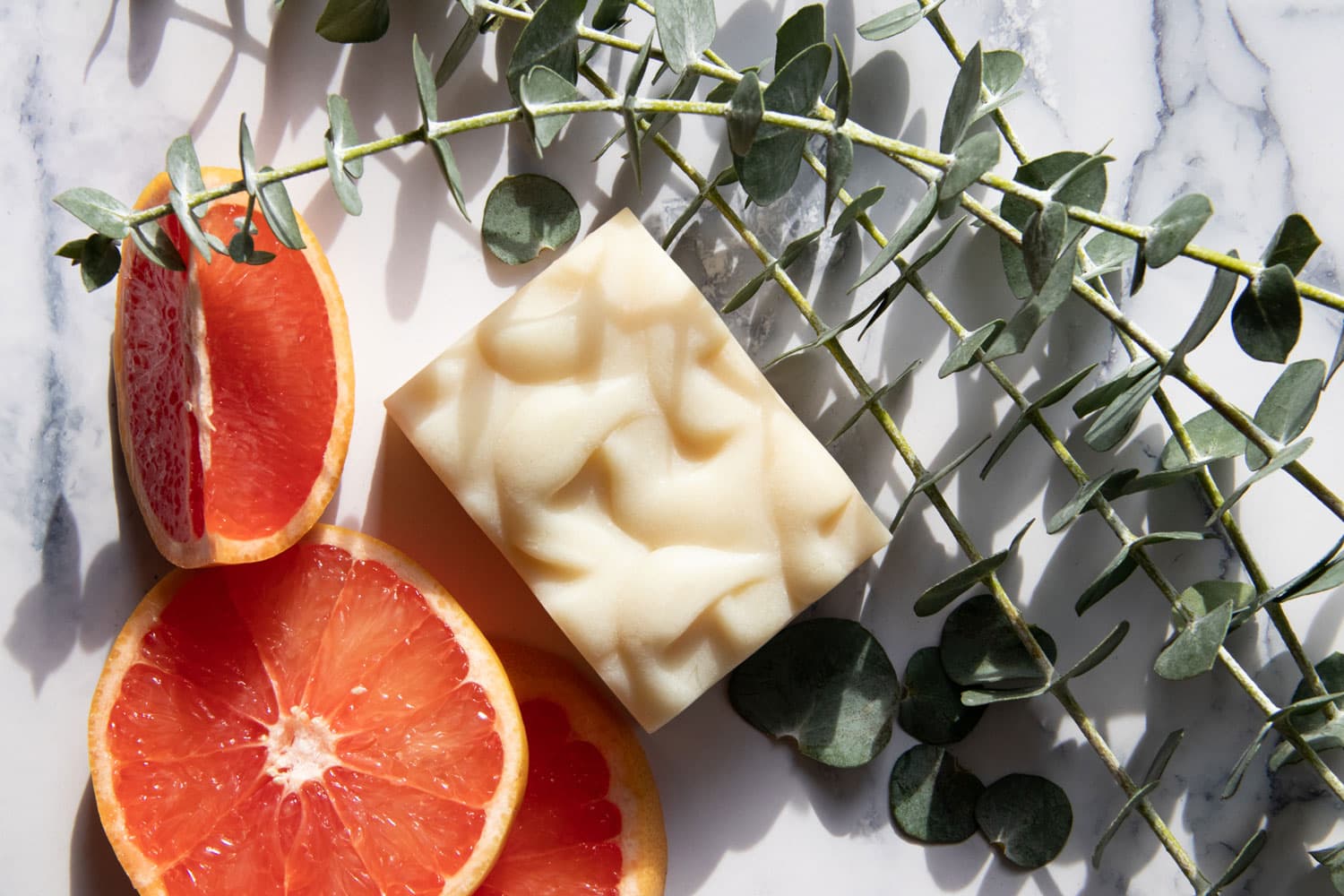 A textured bar of organic soap made by Osmia in Carbondale is modeled with slices of grapefruit and sprigs of greenery.