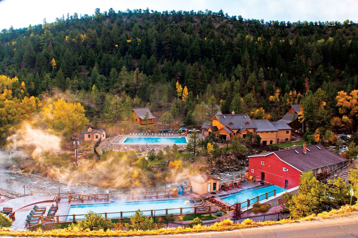 Fall colors begin to show in the foliage around Mount Princeton Hot Springs Resort in Colorado. Steam billows up and drifts away from the toasty hot spring pools.