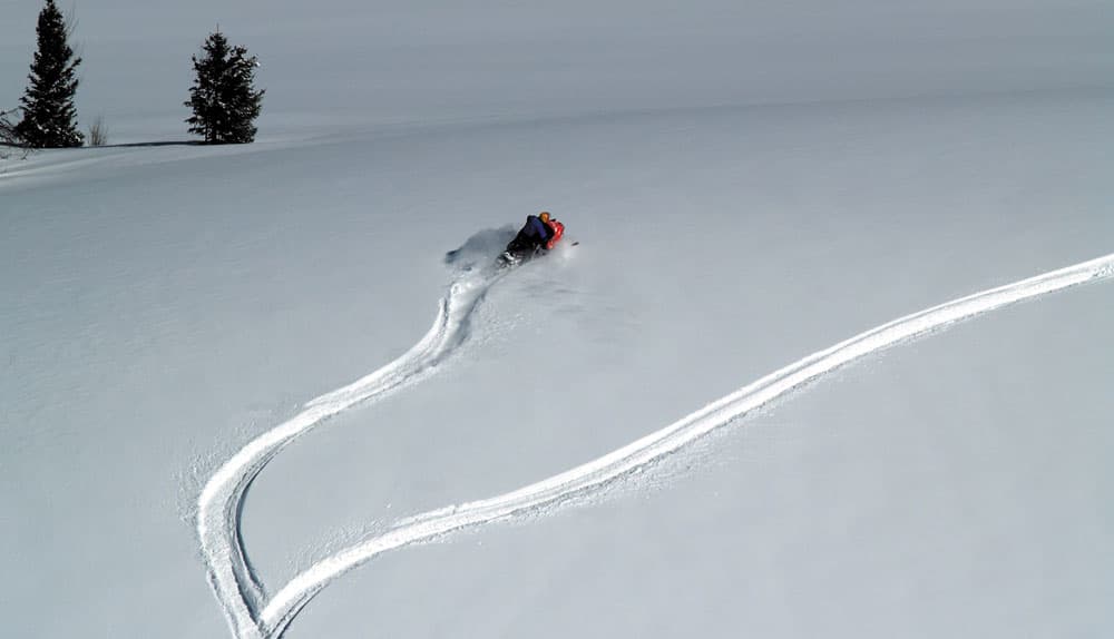 A snowmobile makes new tracks through fresh snow
