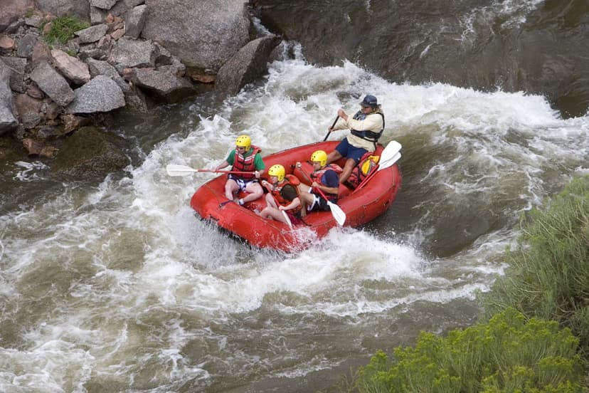 Four people in helmets and life vests ride the rushing, whitewater waves of the Arkansas River near Cañon City, Colorado.