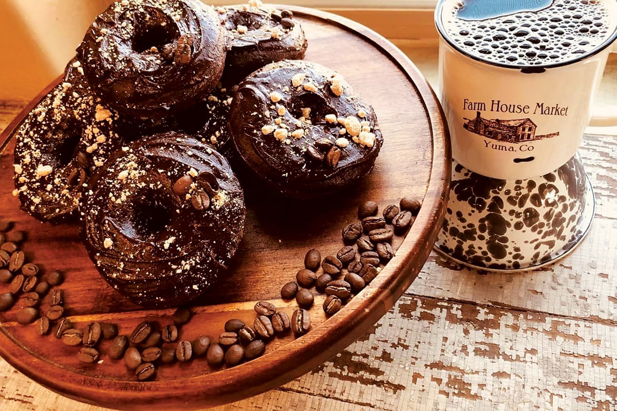 A plate of chocolate-covered donuts with a cup of coffee