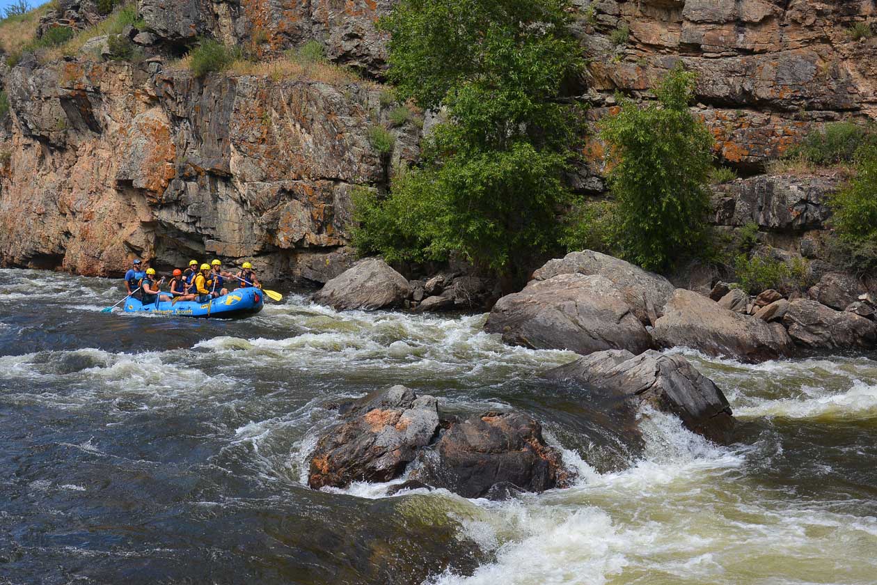 A blue raft hits whitewater while trying to avoid rocks in the river