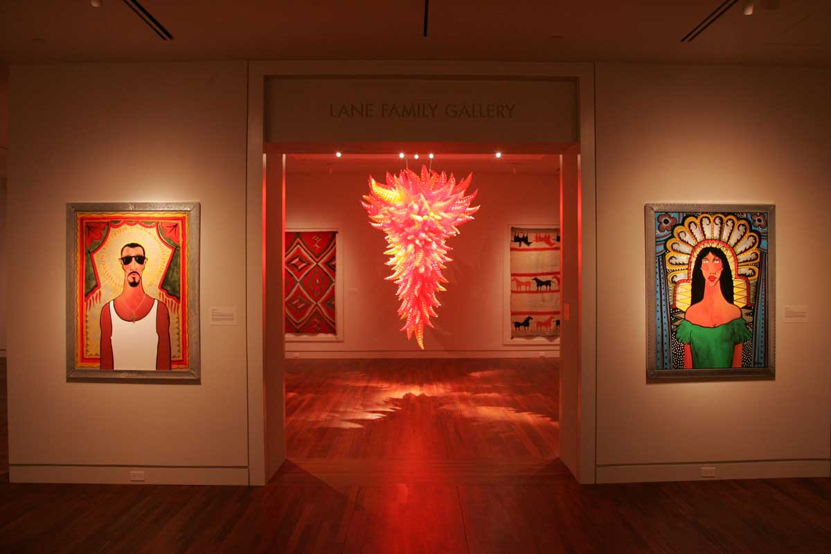 A gallery with a bright-red glass chandelier and two paintings on either sidee