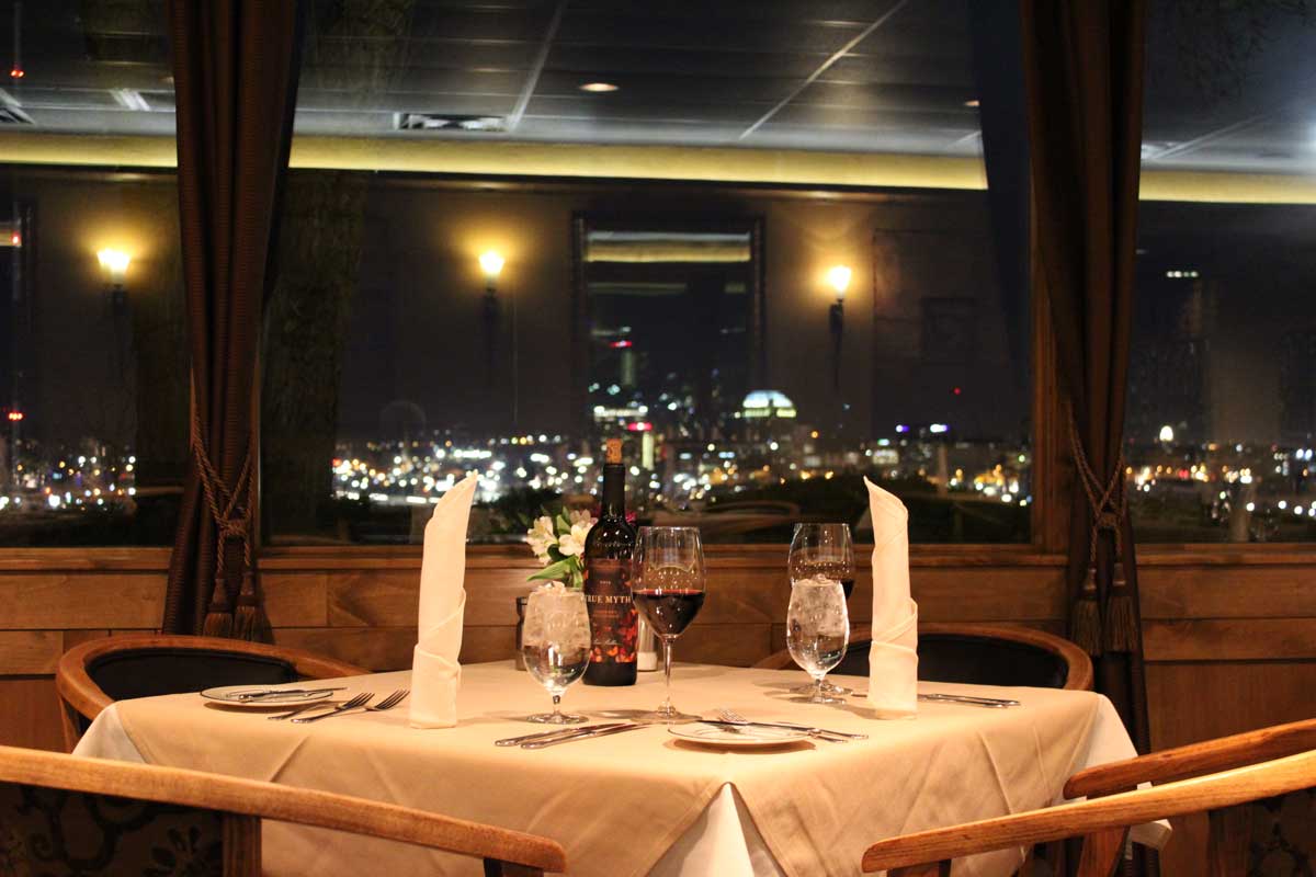 A table set for two in front of a window that looks over the city lights at night