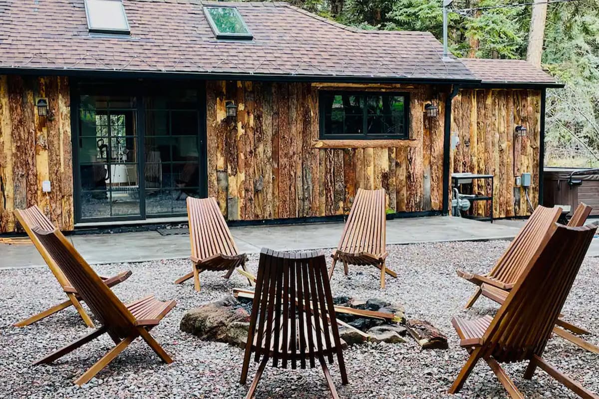 Contemporary outdoor chairs sit in a ring outside a tree-bark shingled cabin near Conifer, Colorado.