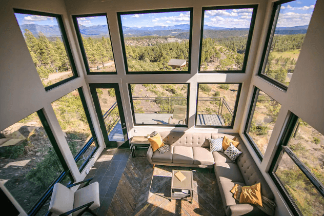 The living room of The Ridge cabin in Pagosa Springs is filled with natural light from panoramic windows.