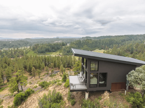 The side view of The Ridge cabin in Pagosa Springs with trees, shrubbery and a cloud-filled sky